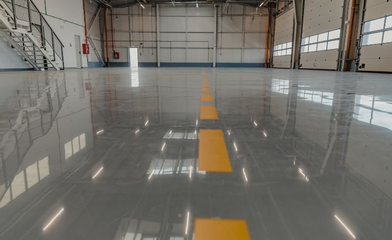 A large warehouse with a reflective floor and yellow lines, representing Epoxy Flooring Services in Chicago, IL.