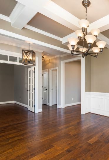 A large, vacant room with polished hardwood floors and white walls, highlighting flooring services in Chicago, IL.