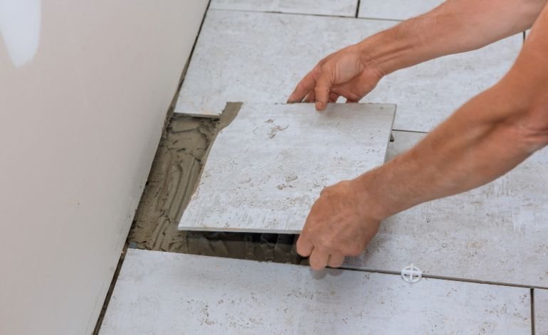 A man is engaged in installing floor tiles, highlighting tile flooring services in Chicago, IL.