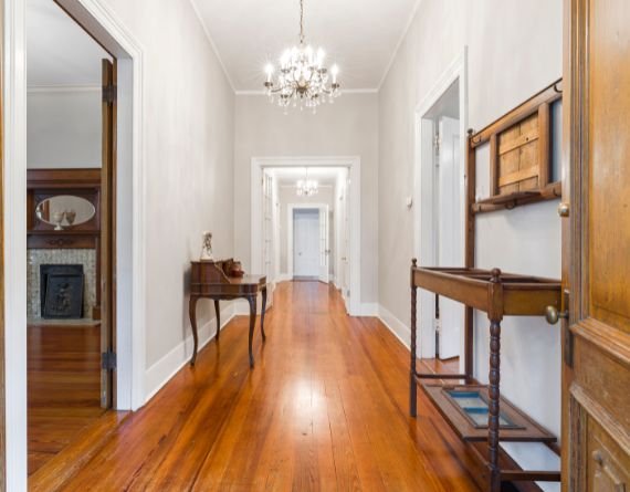 A hallway adorned with wood flooring and a chandelier, highlighting flooring services available in Chicago, IL.